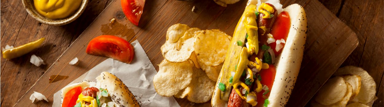 Hot dogs and chips on a wooden board.